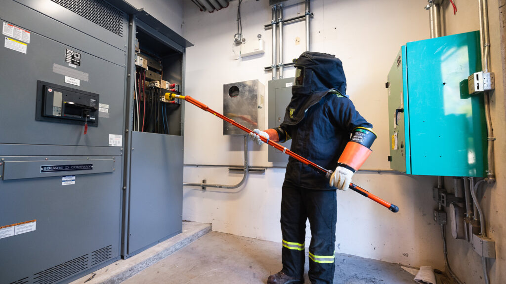 Houle electrician performing electrical preventative maintenance for a facility